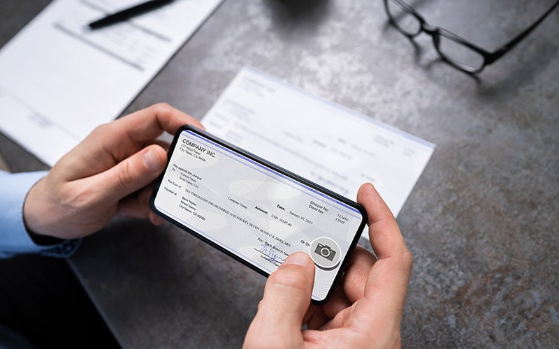 Closeup of hands taking a photo of a check with a smartphone