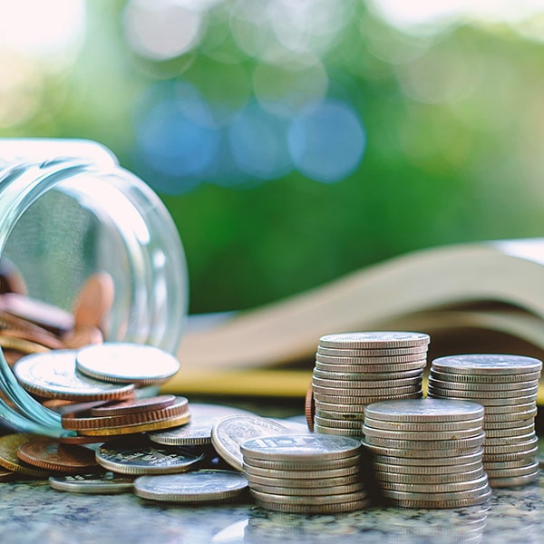 Stack of coins in a jar next to a school book