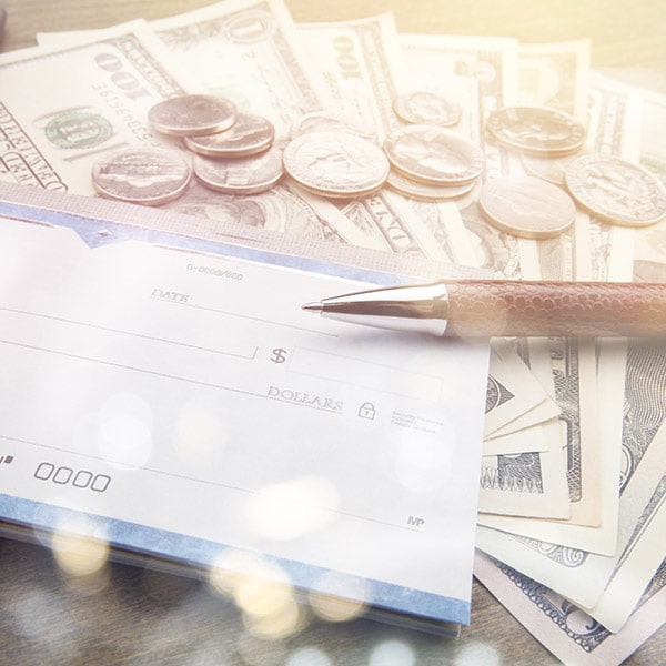 A check and a pen on top of a stack of money